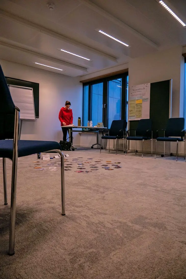 Eine Frau im roten Pullover sortiert Karten in einem Raum