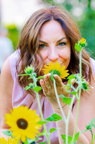 Ramona Leis - Pädagogin für Mindset-Entwicklung - Nahaufnahme von einer Frau, die an Sonnenblumen riecht