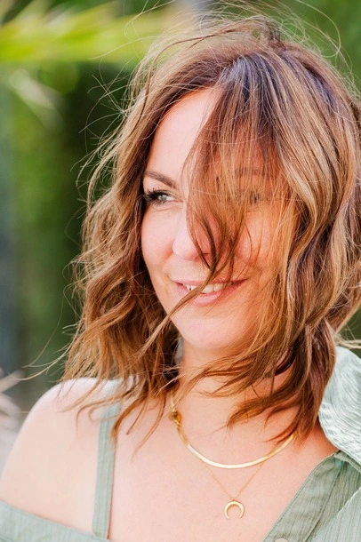 Ramona Leis - Pädagogin für Mindset-Entwicklung - Nahaufnahme von einer Frau mit welligem, braunen Haar, das in das Gesicht weht